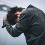 man in black long sleeve shirt covering his face