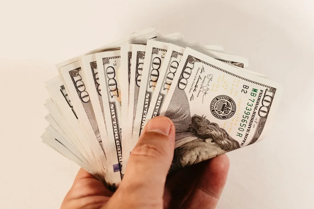 a hand holding a bundle of twenty dollar bills