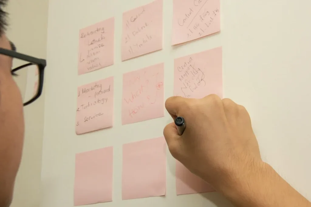 man writing on post note on wall