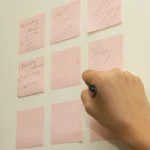 man writing on post note on wall