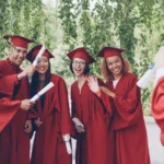 Graduates in red robes pose for a photo outdoors