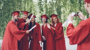 Graduates in red robes pose for a photo outdoors