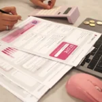 Someone is doing taxes with a calculator and laptop.