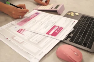 Someone is doing taxes with a calculator and laptop.