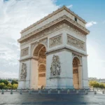 The arc de triomphe in paris under a blue sky.
